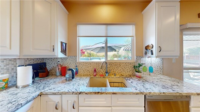 kitchen with dishwasher, decorative backsplash, white cabinetry, and sink