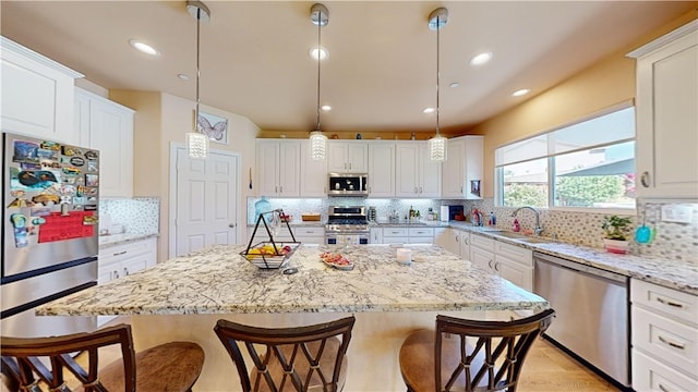 kitchen featuring pendant lighting, a center island, white cabinets, sink, and stainless steel appliances