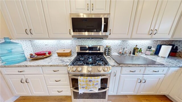 kitchen featuring backsplash, white cabinetry, sink, and appliances with stainless steel finishes