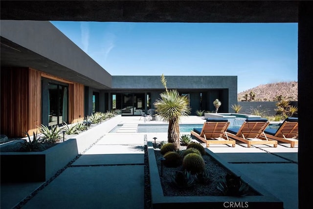 view of patio / terrace with a mountain view and a pool with hot tub