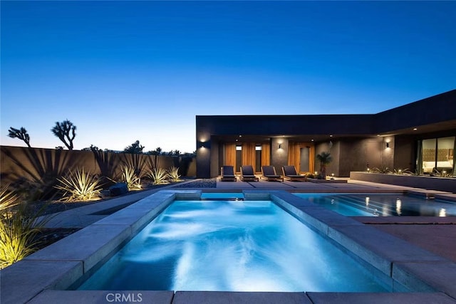 pool at dusk with a patio area