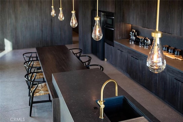 bar with pendant lighting, black oven, and sink