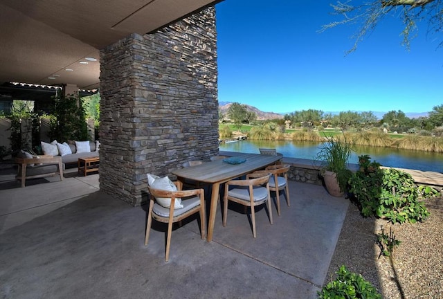 view of patio with a water and mountain view and an outdoor stone fireplace