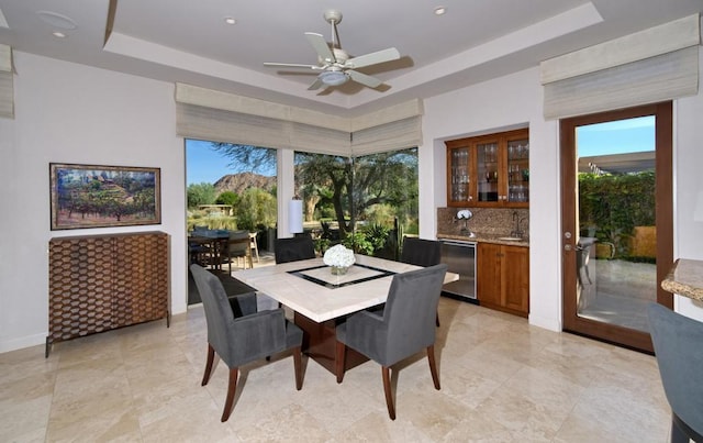 dining room featuring ceiling fan, sink, and a raised ceiling