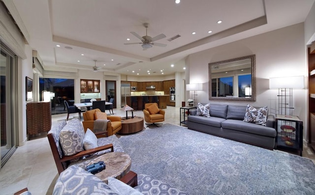 tiled living room featuring a raised ceiling and ceiling fan