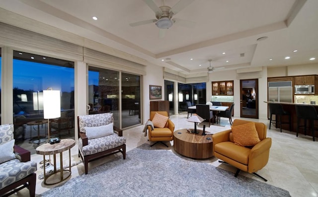 living room with ceiling fan and a raised ceiling