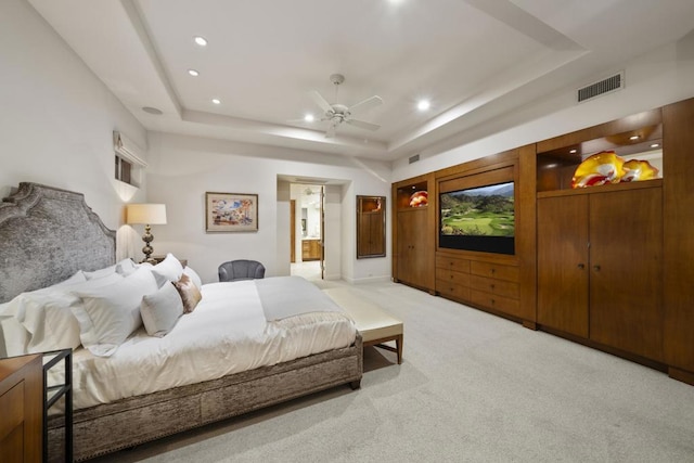 bedroom with a raised ceiling, light colored carpet, and ceiling fan