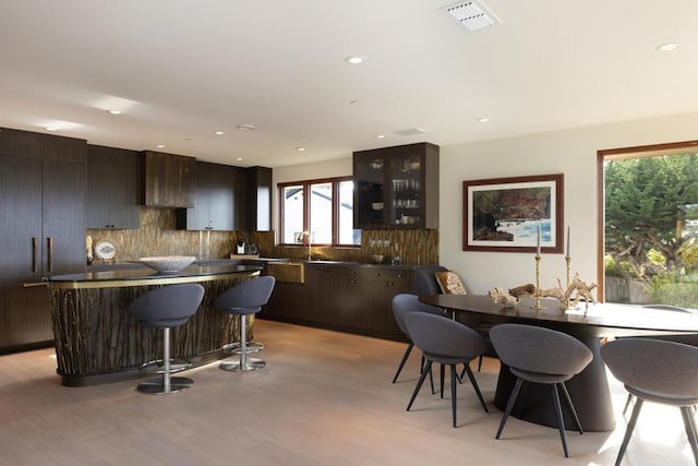 kitchen featuring sink, dark brown cabinets, light hardwood / wood-style floors, and a breakfast bar area