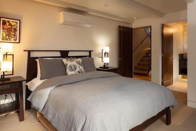 bedroom with beamed ceiling, a wall unit AC, and light hardwood / wood-style flooring