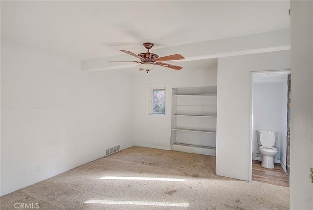 unfurnished bedroom featuring ceiling fan, ensuite bathroom, and light hardwood / wood-style flooring