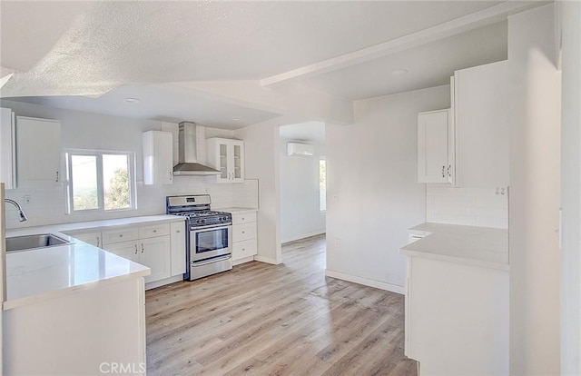 572 Church Hill Rd, La Habra Heights, CA 90631 - kitchen with wall chimney range hood, stainless steel range with gas cooktop, backsplash, white cabinetry, and beam ceiling