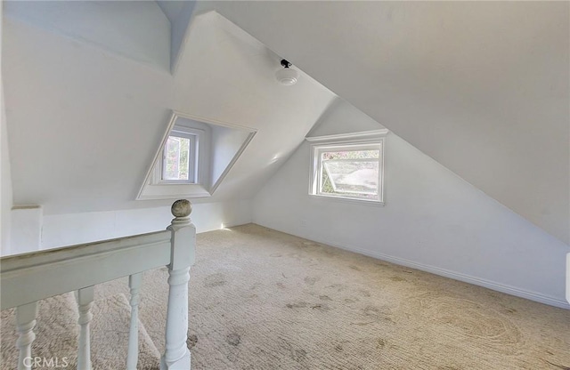 additional living space with lofted ceiling, light colored carpet, and a healthy amount of sunlight