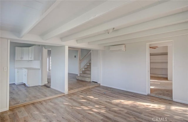 interior space featuring beam ceiling, light wood-type flooring, and a wall unit AC