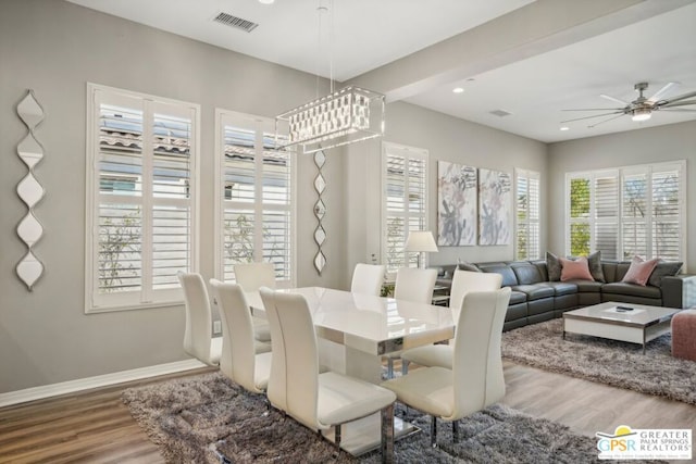 dining area featuring wood-type flooring and ceiling fan with notable chandelier