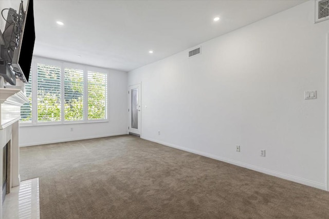 spare room featuring a brick fireplace and light carpet