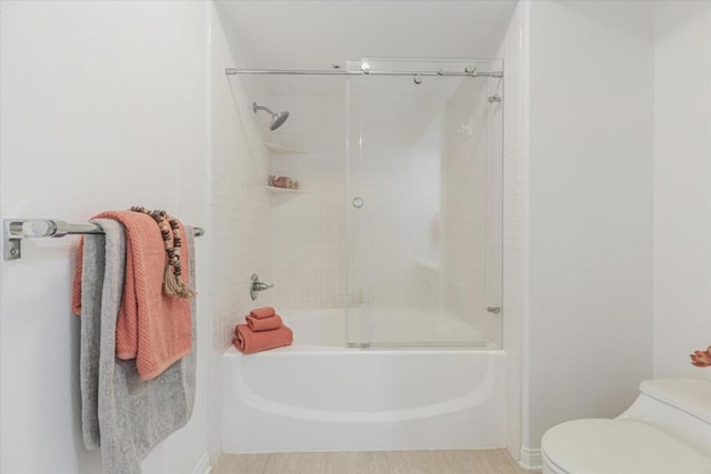 bathroom with enclosed tub / shower combo and toilet