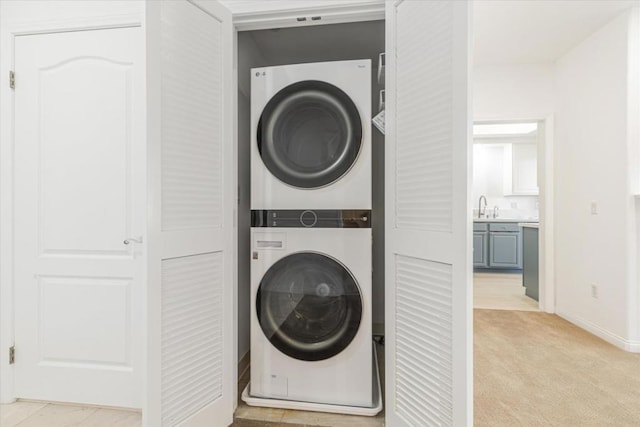 washroom with light carpet, sink, and stacked washer and clothes dryer