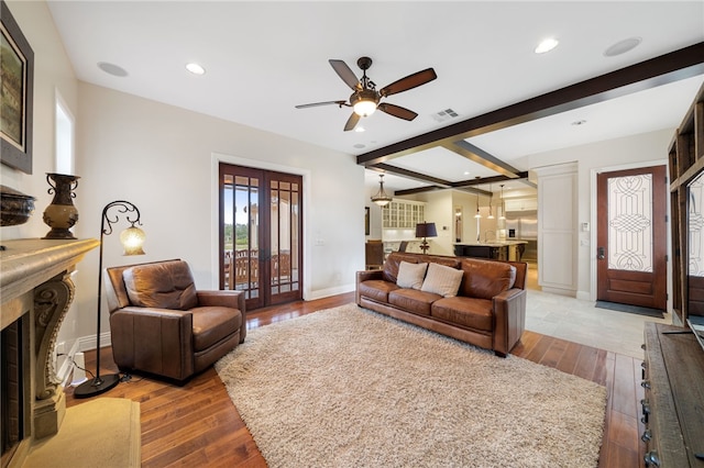 living room with ceiling fan, beam ceiling, a premium fireplace, and hardwood / wood-style floors