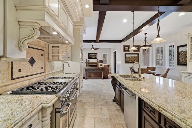 kitchen with light stone countertops, appliances with stainless steel finishes, decorative light fixtures, and sink