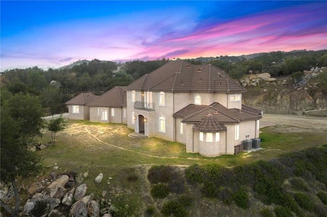 18378 Avenida Bosque, Murrieta, CA 92562 - back of house at dusk with dirt driveway, stucco siding, a tile roof, and central AC