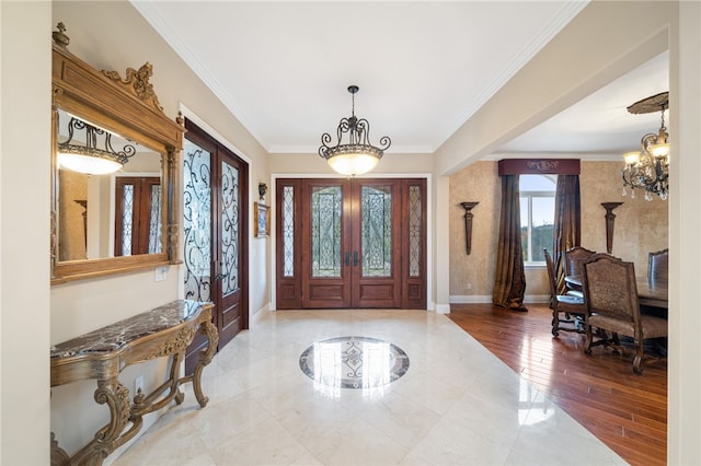 entryway featuring french doors, crown molding, light hardwood / wood-style floors, and a chandelier