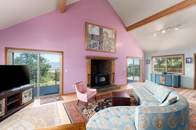 living room with a wood stove, plenty of natural light, and beamed ceiling