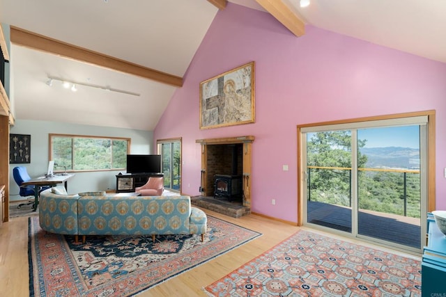 living room featuring high vaulted ceiling, light wood-type flooring, beamed ceiling, and a wood stove