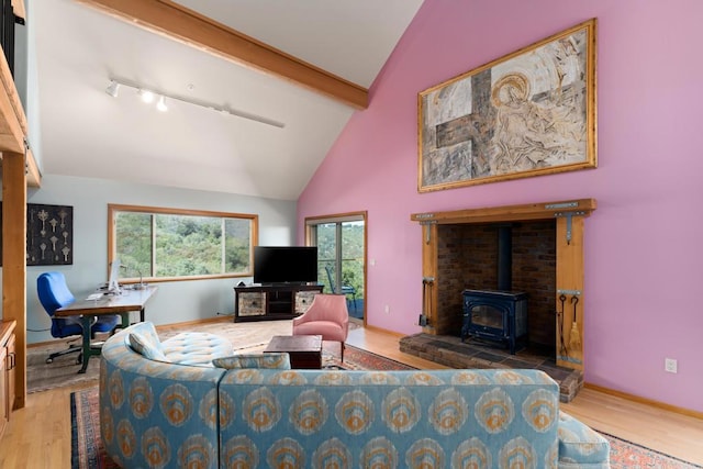 living room featuring track lighting, light hardwood / wood-style floors, a wood stove, and beamed ceiling