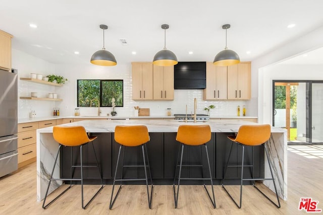 kitchen with ventilation hood, light brown cabinets, light wood-type flooring, and pendant lighting