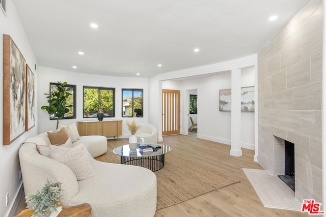 living room featuring a tile fireplace and light hardwood / wood-style floors