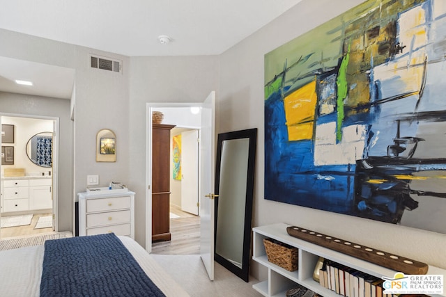 bedroom with ensuite bathroom and light hardwood / wood-style flooring