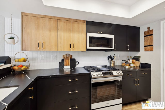 kitchen with tasteful backsplash, light wood-type flooring, light brown cabinetry, and stainless steel range with gas stovetop