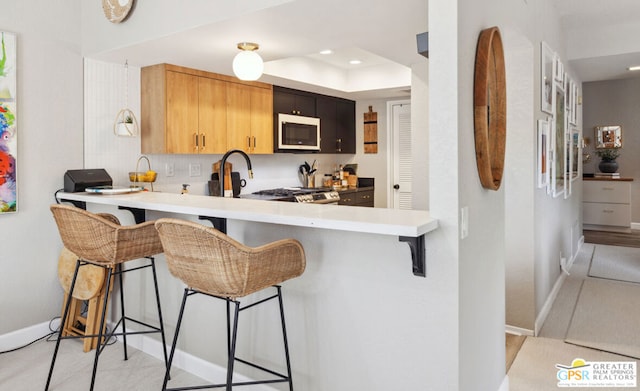 kitchen with kitchen peninsula, stainless steel appliances, a breakfast bar area, and tasteful backsplash