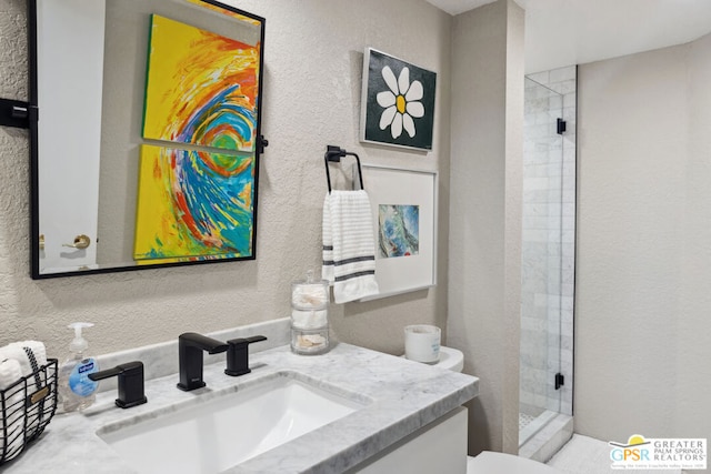 bathroom with a tile shower, vanity, and toilet