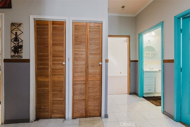 hallway featuring sink, light tile patterned flooring, and crown molding