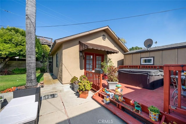 rear view of property featuring a hot tub, a patio, and a deck