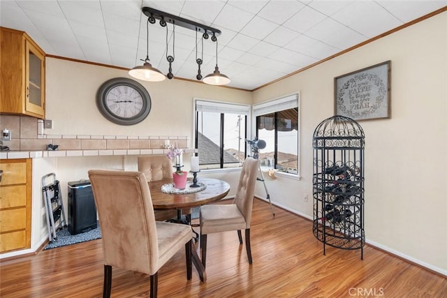 dining area with ornamental molding and light hardwood / wood-style flooring