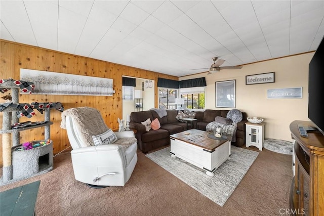 living room with ceiling fan, wooden walls, and carpet