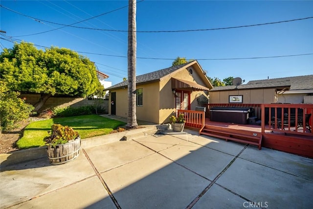 back of property featuring a wooden deck, a yard, a patio area, and a jacuzzi