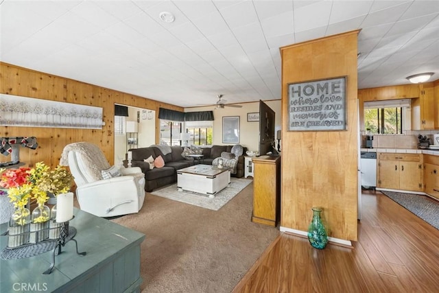 living room with hardwood / wood-style flooring, ceiling fan, a wealth of natural light, and wooden walls