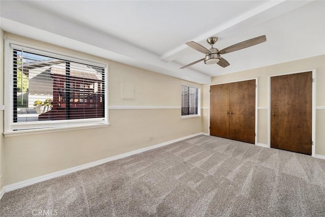 unfurnished bedroom featuring two closets, ceiling fan, and carpet flooring