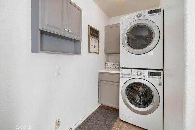 laundry area with cabinets, stacked washer / drying machine, and tile patterned floors