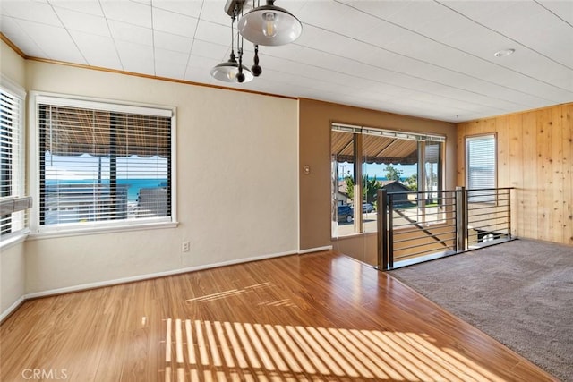 spare room featuring hardwood / wood-style flooring, ornamental molding, and wood walls