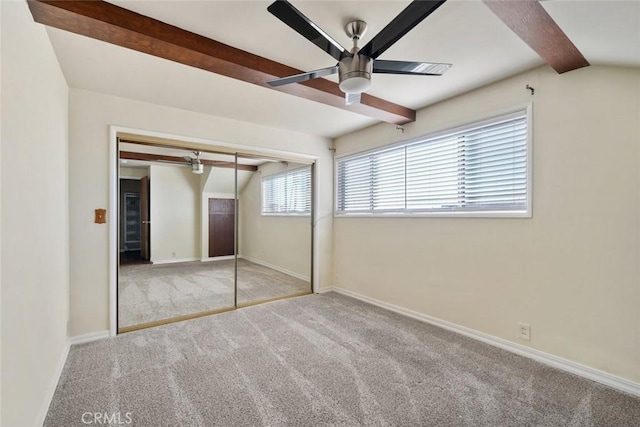 unfurnished bedroom featuring ceiling fan, light colored carpet, beam ceiling, and a closet