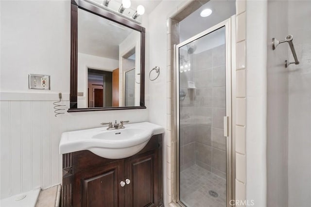 bathroom featuring a shower with door and vanity