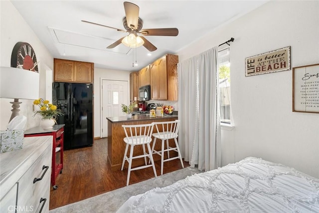 bedroom with dark hardwood / wood-style flooring and black fridge with ice dispenser