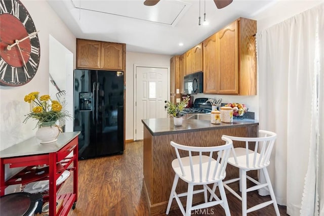 kitchen with a kitchen breakfast bar, dark hardwood / wood-style flooring, kitchen peninsula, and black appliances