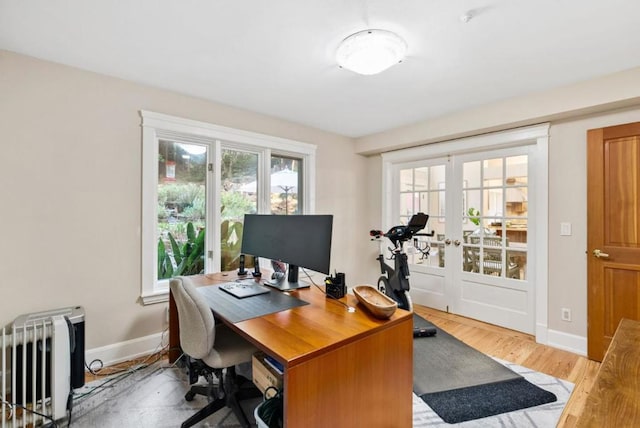 home office featuring radiator heating unit, french doors, and light wood-type flooring