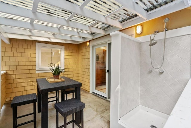 interior space with a shower, concrete flooring, and tile walls