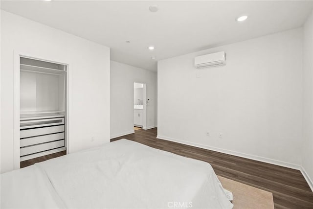 bedroom with a closet, dark wood-type flooring, and a wall mounted air conditioner